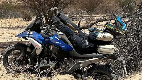 Eine Fahrerin des japanischen Frauenteams liegt auf ihrer R 1300 GS. Die Beine zeigen in Richtung des Lenkers, während die Schultern und der Kopf über das Heck des Motorrads hinausschauen.