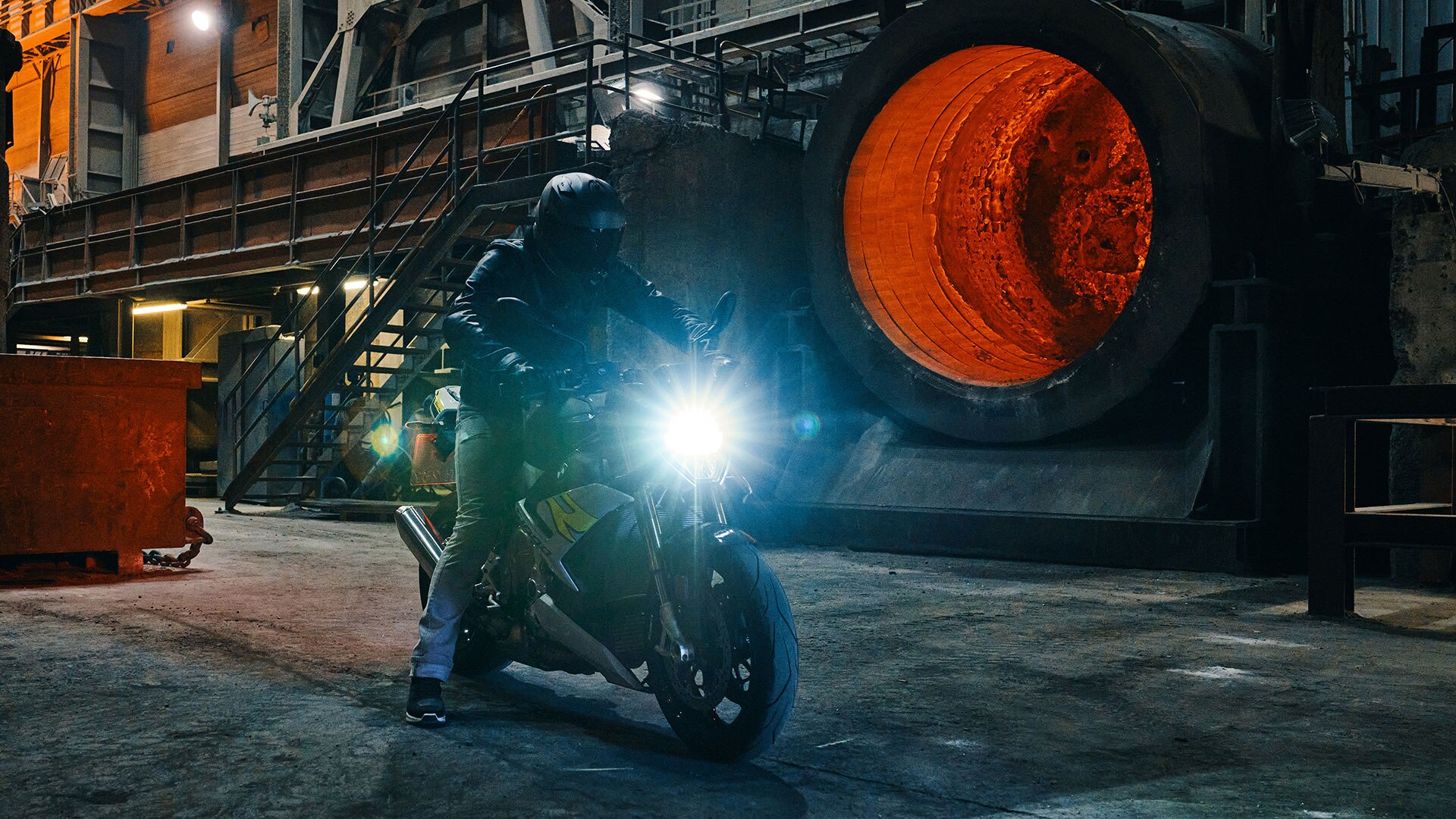 Wir sehen den S 1000 R vor einem glühenden Stahlkessel.